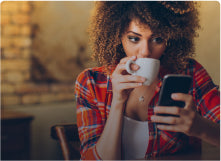 Woman in red flannel drinking coffee and looking at her phone